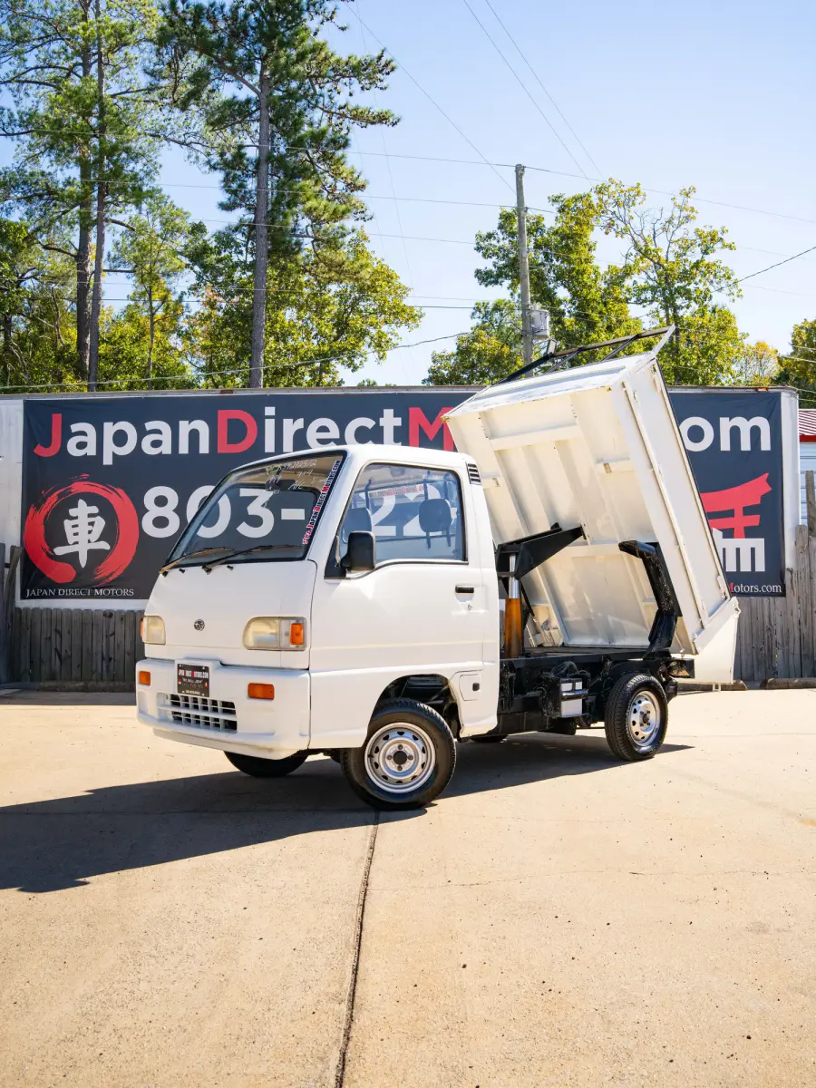 White 1994 Subaru Sambar Dump Bed 4x4 Kei Truck, front three-quarter view with dump bed raised, for sale at Japan Direct Motors in Irmo, SC