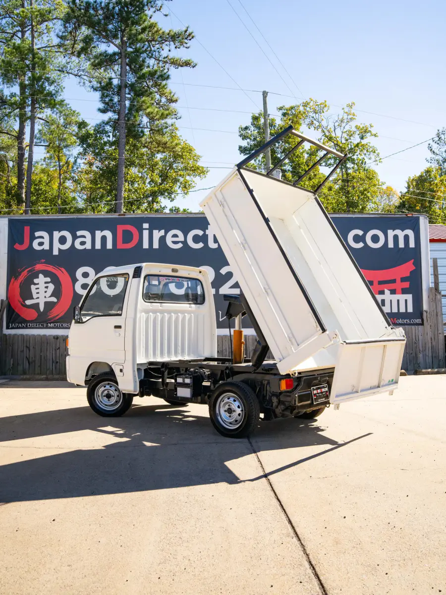 White 1994 Subaru Sambar Dump Bed 4x4 Kei Truck, rear three-quarter view with dump bed raised, for sale at Japan Direct Motors in Irmo, SC