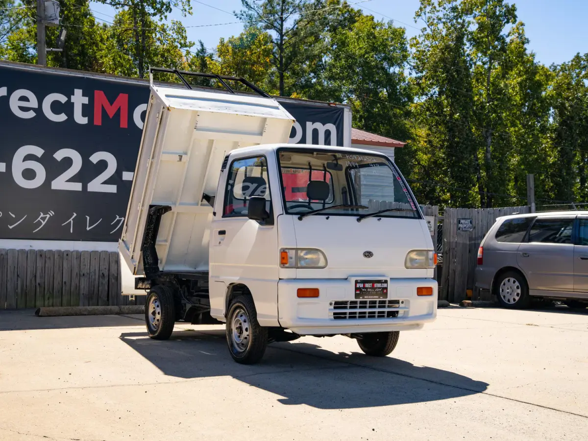 White 1994 Subaru Sambar Dump Bed 4x4 Kei Truck, front three-quarter view with dump bed raised, for sale at Japan Direct Motors in Irmo, SC