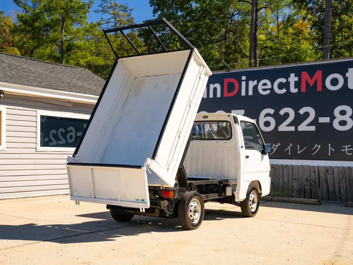White 1994 Subaru Sambar Dump Bed 4x4 Kei Truck, rear three-quarter view with raised dump bed, for sale at Japan Direct Motors in Irmo, SC