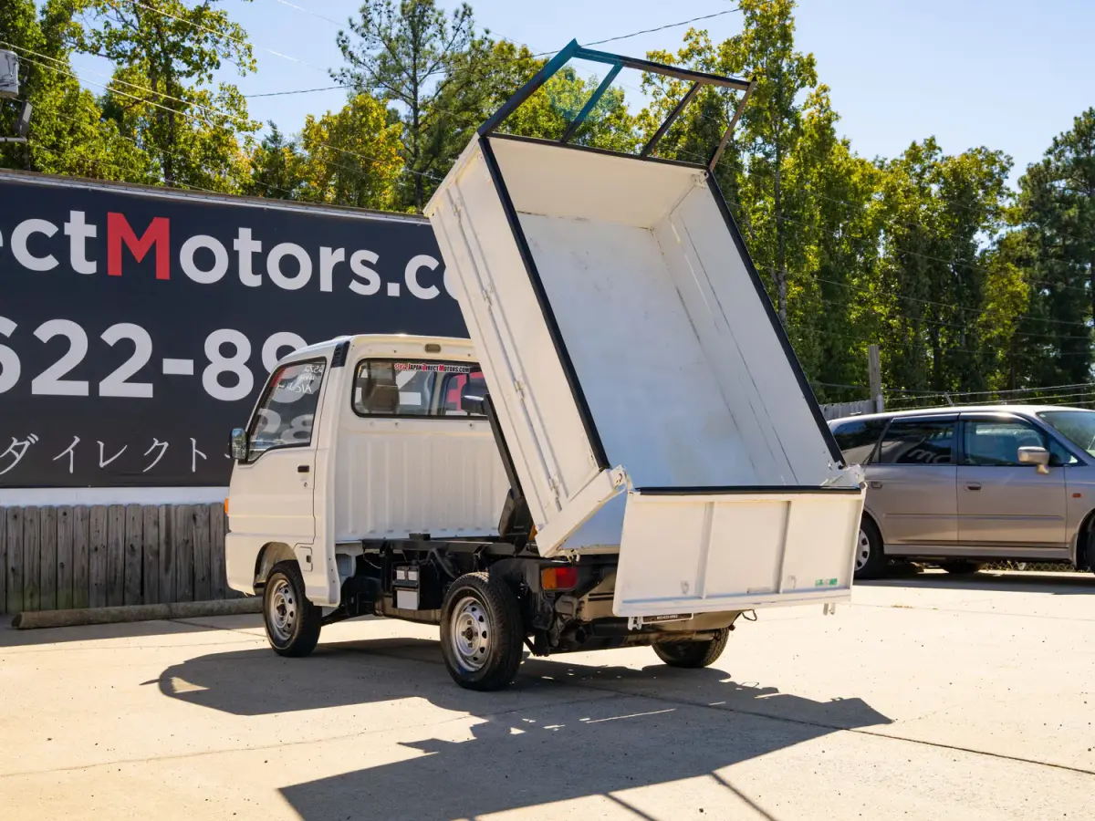 White 1994 Subaru Sambar Dump Bed 4x4 Kei Truck, rear three-quarter view with raised dump bed, for sale at Japan Direct Motors in Irmo, SC